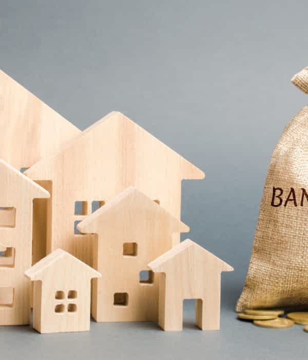 A money bag with the word Bankruptcy, a down arrow and wooden houses