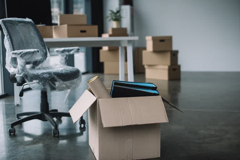 cardboard box with folders and office supplies in floor during relocation